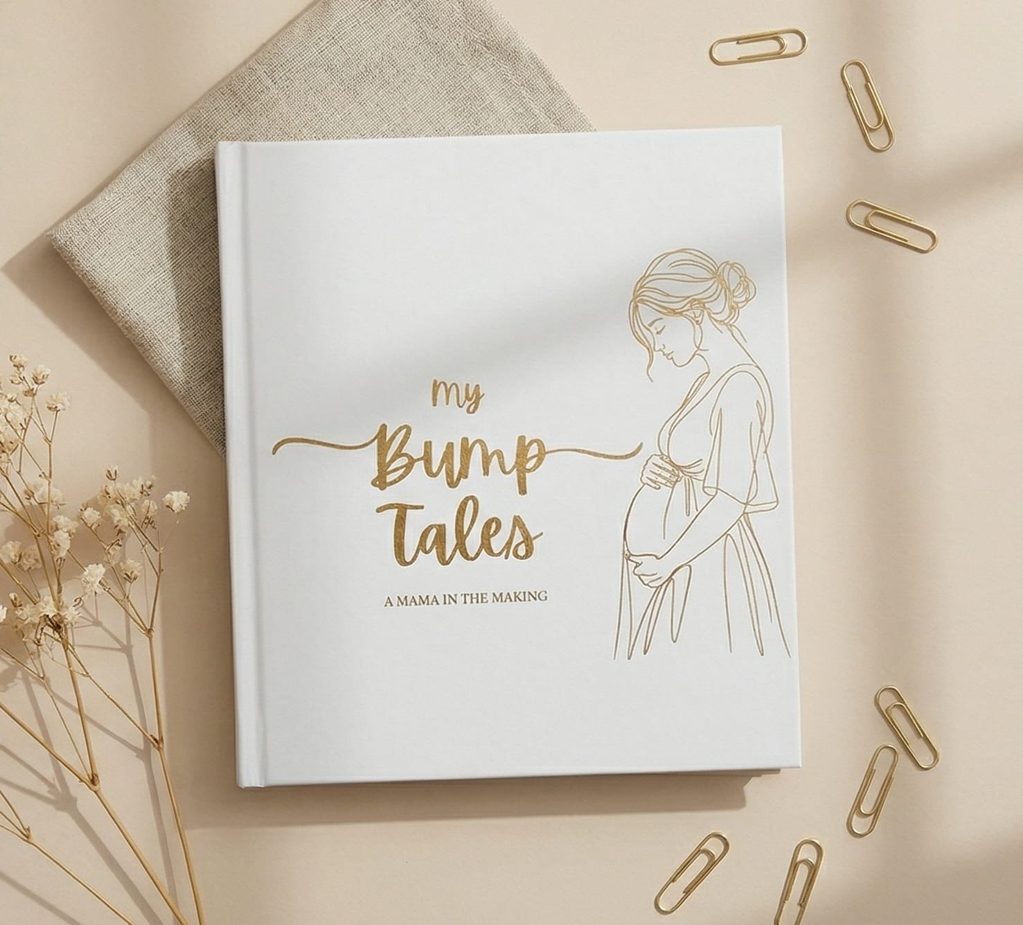 My Bump Tales journal flat lay with gold paper clips and flowers